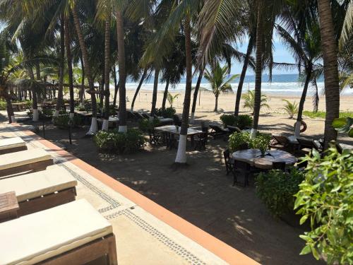 a view of a beach with tables and palm trees at Puertas Paraíso Hotel boutique in Zihuatanejo