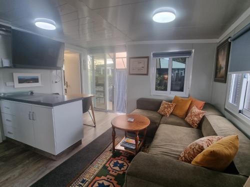 a living room with a couch and a kitchen at Pukeko Cottage in Richmond