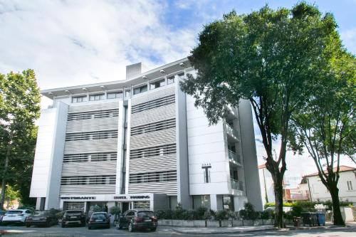 a white building with cars parked in front of it at Hotel Touring in Carpi