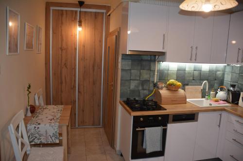 a kitchen with white cabinets and a table and a stove at LélekZug Mátra in Parádsasvár