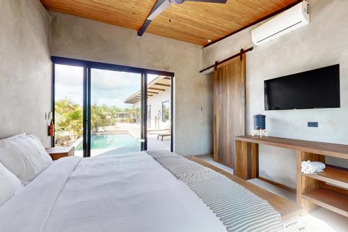 a bedroom with a large bed with a flat screen tv at Seabird - Villa 20 in Placencia Village