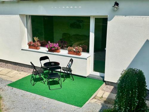 a patio with a table and chairs on a green rug at Dolpo 55 in Benešov
