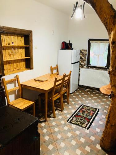 a kitchen with a table and chairs and a refrigerator at Pensiunea Agroturistica Cerna, Vaideeni - Polovragi in Vaideeni
