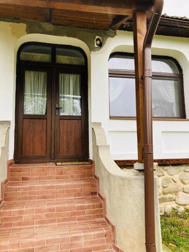 a house with a wooden door and stairs at Pensiunea Agroturistica Cerna, Vaideeni - Polovragi in Vaideeni