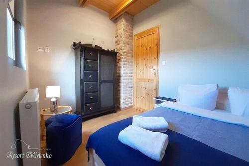 - une chambre avec un lit bleu et une commode noire dans l'établissement Holiday home with garden, sauna, jacuzzi, à Mielenko