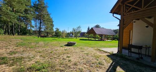a yard with a building and a bench in a field at Leśna Przystań Bory Tucholskie in Łuby