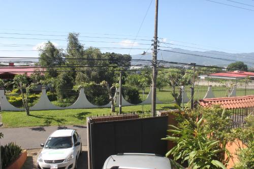 a white car parked in a yard with a fence at Hotel Santa Maria Inn in Alajuela City