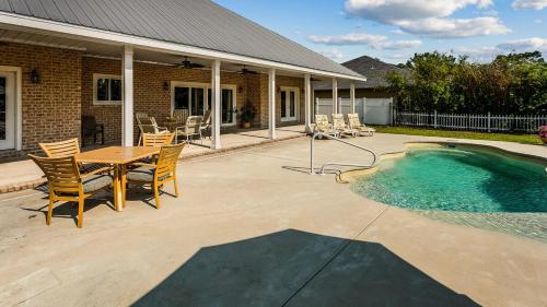 een terras met een tafel en stoelen naast een zwembad bij DreamBoat Paradise Heated Pool- Hot Tub near Beach in Pensacola