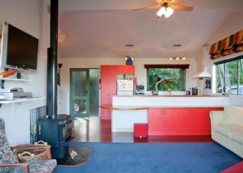 a living room with a kitchen with a stove at Kereru Hill in Palm Beach