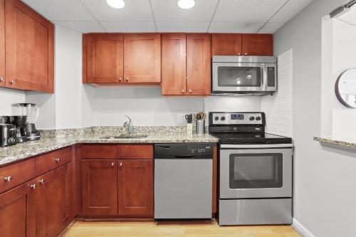 a kitchen with wooden cabinets and a stove and microwave at Modern Comfort Apartment Close to Metro & Shops in Arlington