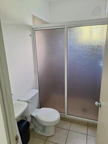 La salle de bains est pourvue de toilettes et d'une porte de douche coulissante. dans l'établissement Apartamento con picina en zona hotelera, à Puerto Vallarta