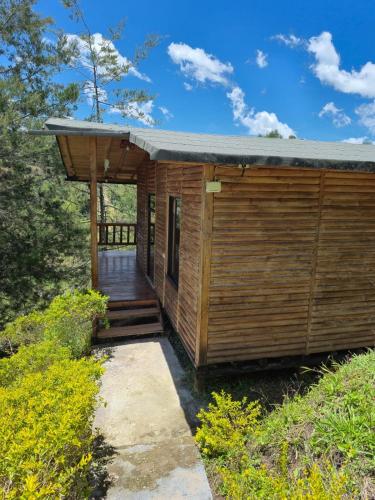 a small wooden cabin with a porch and a deck at Cabina con Jacuzzi cerca al Peñol in Chiquinquirá
