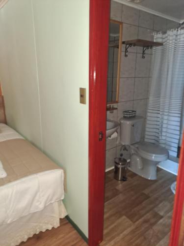 a bedroom with a bed and a bathroom with a toilet at Asói Hostal in Puerto Natales