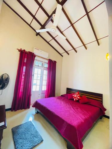 a bedroom with a large purple bed with pink curtains at SAN Holiday in Wadduwa
