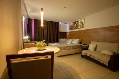a room with a bed and a table and a couch at Suíte luxo com tela de cinema no América Towers Studio Residence in Salvador