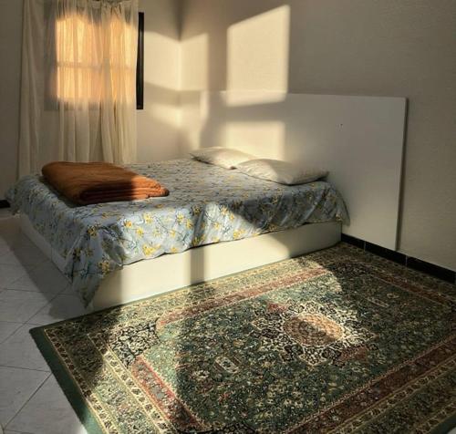 a bedroom with a bed and a rug on the floor at Relaxing stay in a quiet apartment in Laayoune