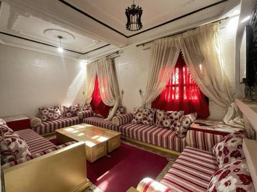 a living room with couches and red curtains at Relaxing stay in a quiet apartment in Laayoune