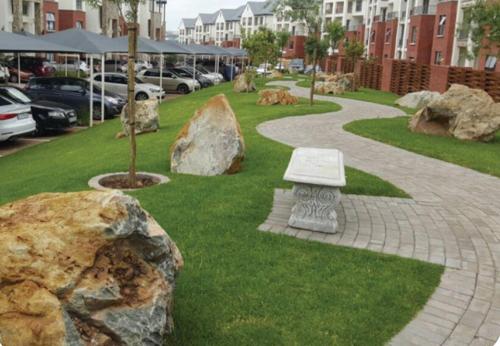 a park with rocks and a bench in the grass at Modern Apartment near OR Tambo Airport in Edendale