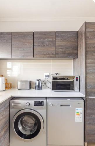 a kitchen with a washing machine and a microwave at Modern Apartment near OR Tambo Airport in Edendale