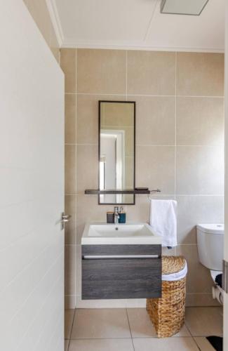 a bathroom with a sink and a mirror at Modern Apartment near OR Tambo Airport in Edendale