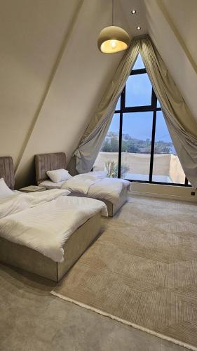 Tres camas en una habitación con una gran ventana. en اكواخ ساوثرنز, en Ḩaḑram