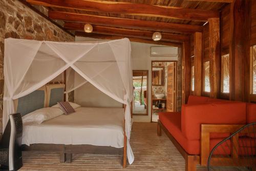 a bedroom with a canopy bed and a red couch at Casa del Mar AC Rustic design Pool Paceful in Santa María Tonameca