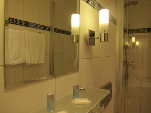 a bathroom with a sink and a shower with a mirror at Hotel-Restaurant Große-Wilde in Bottrop