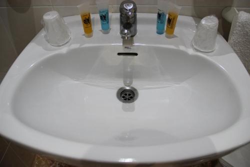 lavabo con grifo y 4 vasos para beber en Hostal la zamora, en Carcabuey