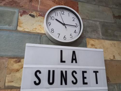 a clock hanging on a wall next to a sign at LA SUNSET in Accra