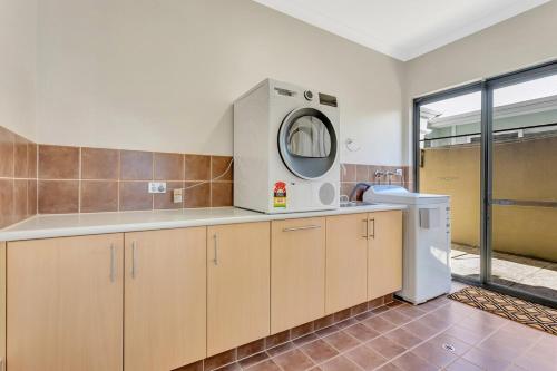 una cucina con lavatrice e asciugatrice in una stanza di Panda Living canal house a Wannanup
