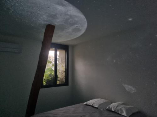 a bedroom with a window with the moon on the wall at Le voyage mystérieux in La Celle-sous-Gouzon