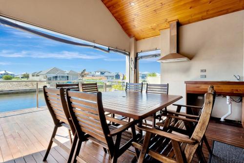 a dining room with a table and chairs on a deck at Panda Living waterfront paradise in Wannanup