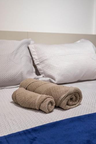 a rolled up towel on a bed with two pillows at Apê com piscina e academia: Metrô 350m in Rio de Janeiro