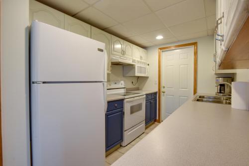 a kitchen with a white refrigerator and blue cabinets at Walk to Lake Winnisquam Access Cozy Retreat in Winnisquam