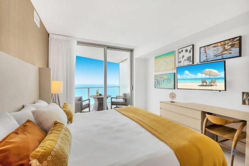 a bedroom with a bed and a desk with a view of the ocean at Beautiful 1BR Apartment with Ocean View Balcony in Hollywood Beach