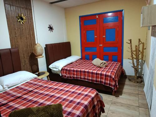 a room with two beds and a red door at Hotel, Casa Calle Real in Salento