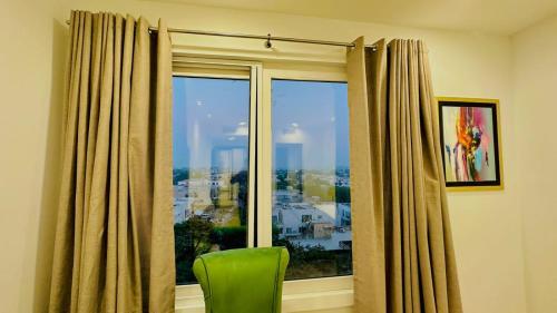 a green chair sitting in front of a window at Gold Crest Mall & Residency Premium Apartments With Al-Fatah Store & Shopping Mall in Lahore