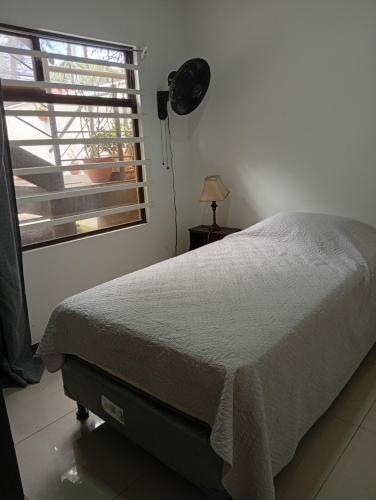 Un dormitorio con una cama y una ventana y una lámpara. en Hospedaje Adrianita, en Pozos