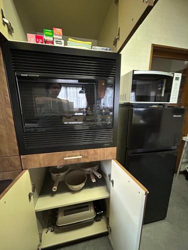 a kitchen with a microwave and a black refrigerator at T'S House Numazu in Numazu