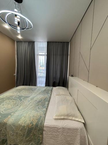 a bedroom with a large bed and a window at Perfect HoLiDaY in Almaty