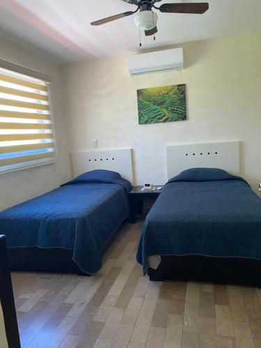 Un dormitorio con dos camas y un ventilador de techo. en Villa 10, en Mazatlán