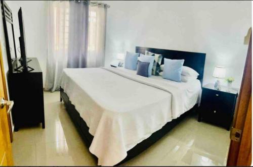 a bedroom with a large white bed with blue pillows at Hermosa Casa familiar en las orquideas LR in La Romana
