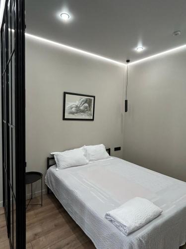 ein Schlafzimmer mit einem weißen Bett und einem Stuhl in der Unterkunft Royal Comfort Business Class Apartment in the heart of the ALMATY CITY in Almaty