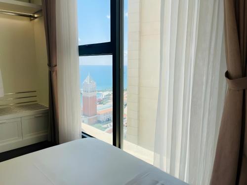 a bedroom with a bed and a large window at Green Hillside Apartment in Phu Quoc