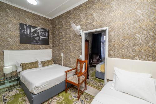 a bedroom with two beds and a chair in it at Prime Executive Accommodation in Cape Town