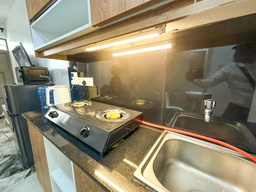 een keuken met een fornuis en een gootsteen en een persoon bij tsavo roysambu in Nairobi