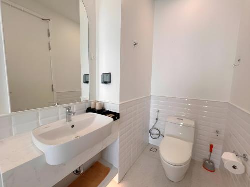 a white bathroom with a sink and a toilet at Green Hillside Apartment in Phu Quoc