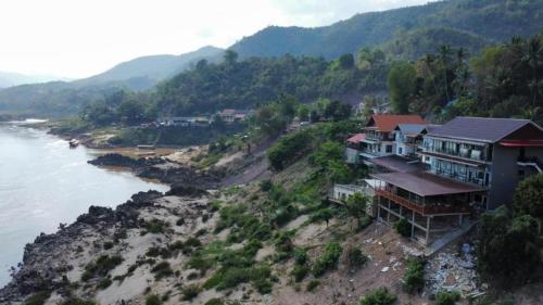a house on a hill next to the water at 2 days Mekong cruise package with Mekong Lover Cruise from Houay Xay to Luang Prabang or Mekong cruise from Luang Prabang to Huay Xai - Thailand in Ban Khonkèo