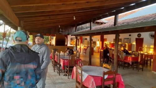 een man en vrouw die voor een restaurant staan bij Pousada Texas Club in Panorama