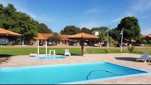 een zwembad in een tuin met stoelen en een huis bij Pousada Texas Club in Panorama